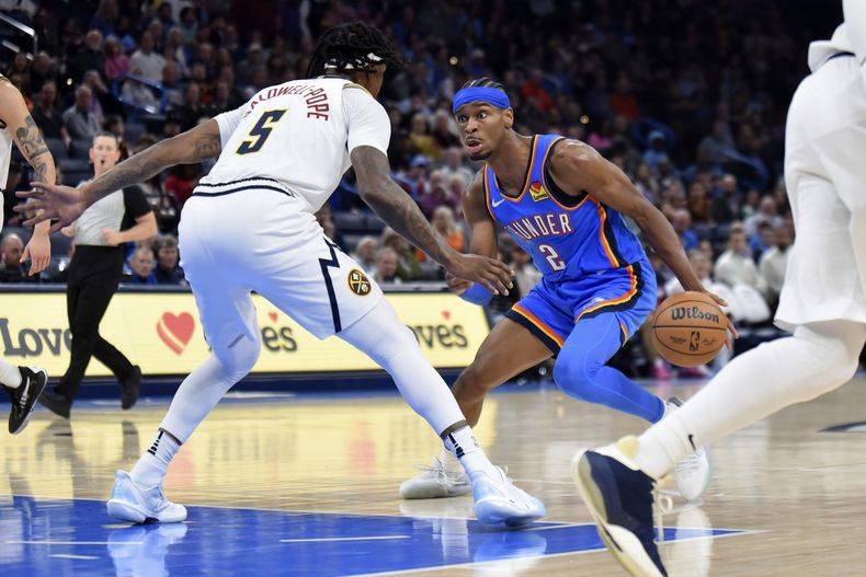 Shai Gilgeous-Alexander, base del Thunder de Oklahoma, busca avanzar frente a Kentavious Caldwell-Pope, de los Nuggets de Denver, el miércoles 31 de enero de 2024 (AP Foto/Kyle Phillips)
