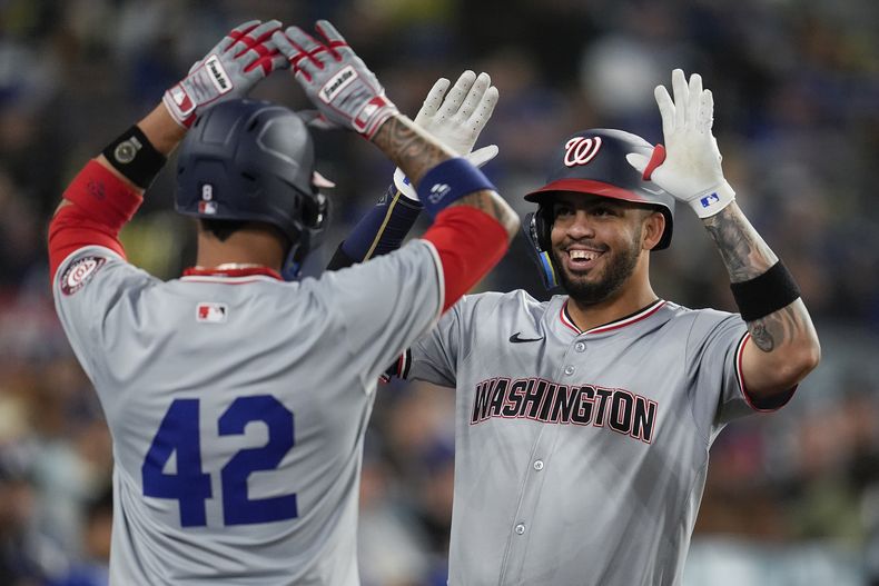 Luis Garcia Jr., derecha, de los Nacionales de Washington, celebra con su compañero de equipo, Eddie Rosario, después de batear jonrón de tres carreras en la quinta entrada del juego de béisbol en contra de los Dodgers de Los Ángeles, el lunes 15 de abril de 2024, en Los Ángeles. (AP Foto/Marcio Jose Sanchez)
