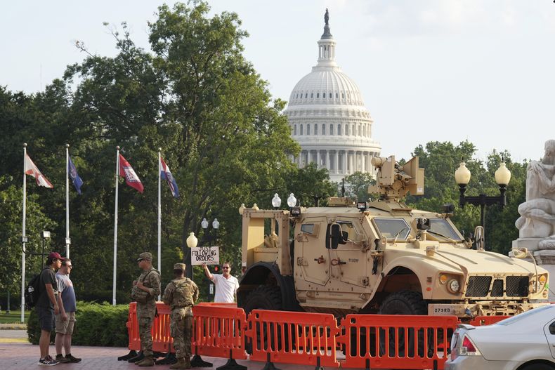 Miembros de la Guardia Nacional vigilan mientras transeúntes llegan a la entrada de Union Station cerca del Capitolio, en Washington, el viernes 15 de agosto de 2025, en Washington. (AP Foto/Jacquelyn Martin)