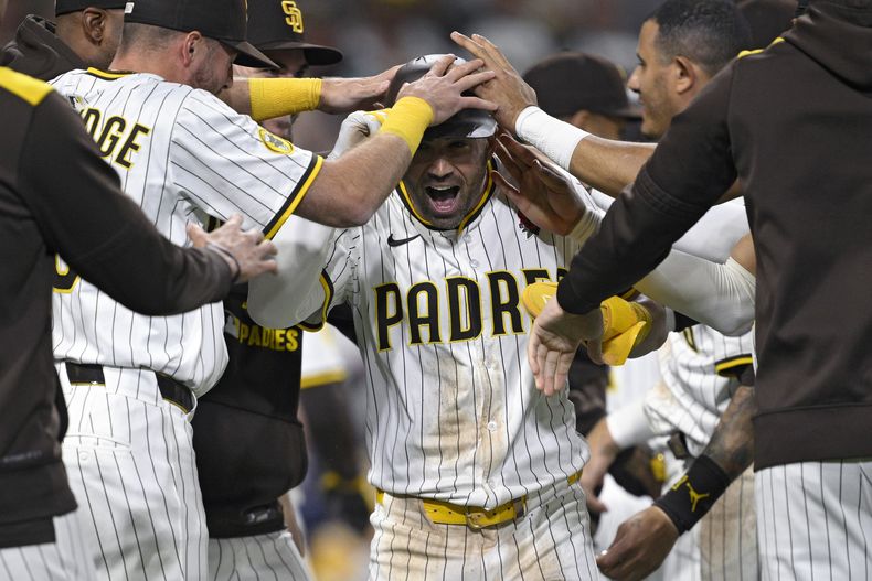 Tyler Wade de los Padres de San Diego es felicitado por sus compañeros tras anotar con un wild pitch en la 11ma entrada ante los Marlins de Miami el luens 26 de mayo del 2025. (AP Foto/Orlando Ramirez)