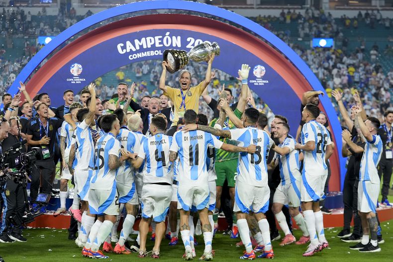 El equipador argentino Mario De Stefano sostiene el trofeo mientras celebra con los jugadores después de derrotar a Colombia en la final de la Copa América en Miami Gardens, Florida, el lunes 15 de julio de 2024. (AP Foto/Rebecca Blackwell)