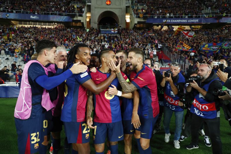 El delantero brasileño Raphinha (tercero a la izquierda) es felicitado por sus compañeros tras anotar el cuarto gol del Barcelona en la victoria 4-1 ante el Bayern Múnich en la Liga de España, el miércoles 23 de octubre de 2024. (AP Foto/Joan Monfort)