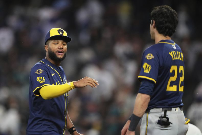 Jackson Chourio (izquierda) de los Cerveceros de Milwaukee saluda a su compañero Christian Yelich (22) tras vencer a los Marineros de Seattle, el lunes 21 de julio de 2025, en Seattle. (AP Foto/Lindsey Wasson)
