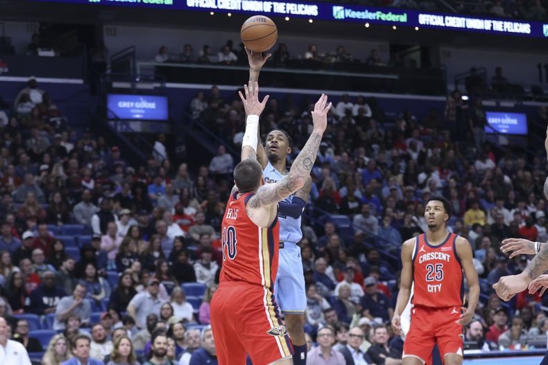 El escolta de los Grizzlies de Memphis, Ja Morant, en el centro, dispara un balón flotante sobre el pívot de los Pelicans de Nueva Orleans, Daniel Theis (10), en la primera mitad de un partido de baloncesto de la NBA en Nueva Orleans, el viernes 27 de diciembre de 2024. (AP Foto/Peter Forest)
