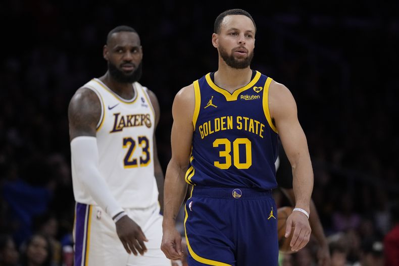 El escolta de los Warriors de Golden State, Stephen Curry (30), y el alero de los Lakers de Los Angeles, LeBron James (23), después de que el juego se detuvo debido a un mal funcionamiento del reloj de tiro durante la segunda mitad del partido de baloncesto de la NBA contra los Golden State Warriors en Los Ángeles, el sábado 16 de marzo de 2024. (AP Foto/Ashley Landis)