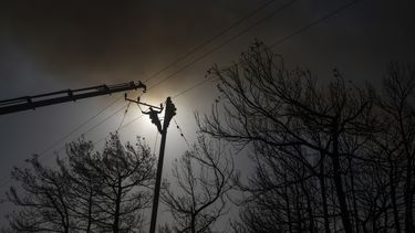 Un trabajador sube a un puesto eléctrico para reparar cables tras un incendio en la localidad de Gennadi, en la isla de rodas, en el sureste de Grecia, el miércoles 26 de julio de 2023. (AP Foto/Petros Giannakouris)