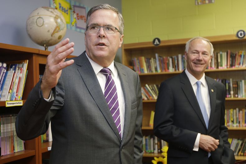 El ex gobernador de Florida Jeb Bush, izquierda, habla con reporteros mientras el candidato republicano a gobernador de Arkansas Asa Hutchinson escucha, en la biblioteca de la LISA Academy North, en Sherwood, Arkansas, el martes 30 de septiembre de 2014.