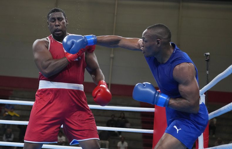 El colombiano Cristian Salcedo lanza un golpe al trinitense Tomas Paul, durante un combate en la categoría de 92 kilogramos en los Juegos Panamericanos de Santiago, el jueves 19 de octubre de 2023 (AP Foto/Martín Mejía)