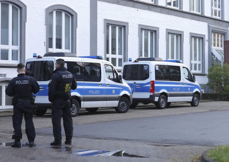 Policías de pie ante un edificio que se está registrando en Solingen, Alemania, el miércoles 17 de abril de 2024. La fiscalía de Düsseldorf detiene a 10 sospechosos en una operación contra una trama internacional de tráfico de personas en ocho estados alemanes. (Gianni Gattus/dpa via AP)