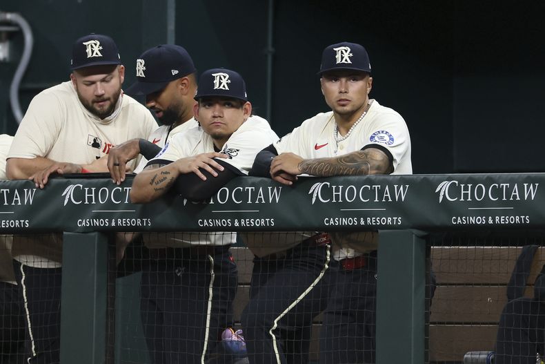 Alejandro Osuna (centro derecha) y Cody Freeman (derecha) de los Rangers de Texas observan el partido de béisbol contra los Tigres de Detroit desde su dugout durante la octava entrada el viernes 18 de julio de 2025, en Arlington, Texas. (AP Photo/Sam Hodde)
