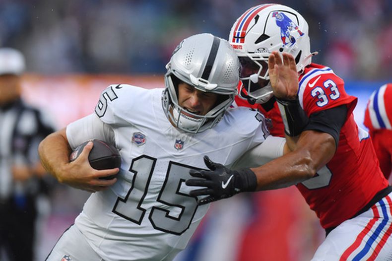 Fernando Mendoza (15), quarterback de los Raiders de Las Vegas, corre con el balón mientras Mike Brown (33), profundo de los Patriots de Nueva Inglaterra busca derribarlo en la segunda mitad del partido de la NFL, el domingo 11 de octubre de 2026. (AP Foto/Steven Senne)