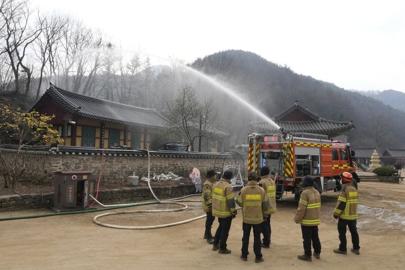 Un camión de bomberos rocía agua como medida de precaución mientras un incendio forestal se acerca a un templo en Cheongsong, Corea del Sur, el jueves 27 de marzo de 2025. (AP Foto/Ahn Young-joon)