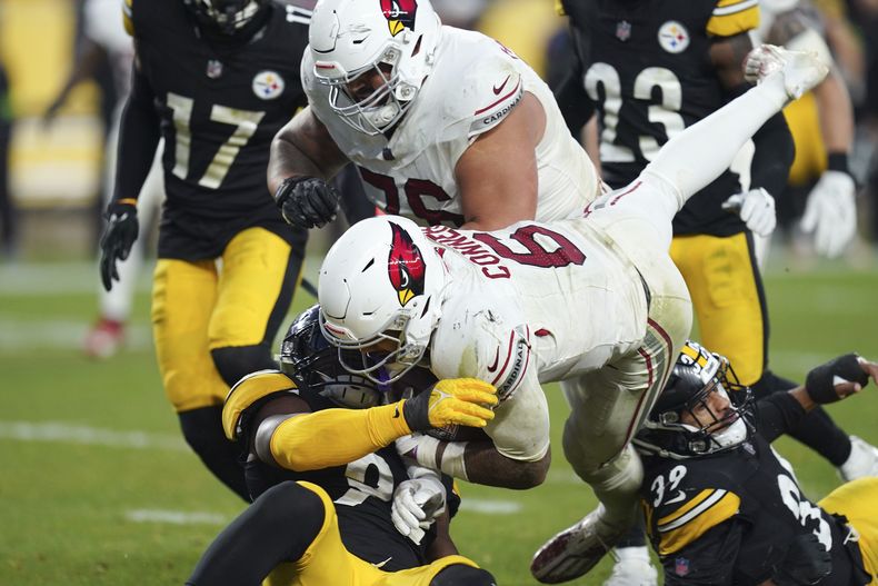 James Conner (6), running back de los Cardinals de Arizona, anota uno de sus dos touchdowns del partido al superar al linebacker Mark Robinson, izquierada, y al safety Minkah Fitzpatrick (39), de los Steelers de Pittsburgh, con la ayuda de Will Hernández durante la segunda mitad del juego de la NFL, el domingo 3 de diciembre de 2023, en Pittsburgh. (AP Foto/Matt Freed)