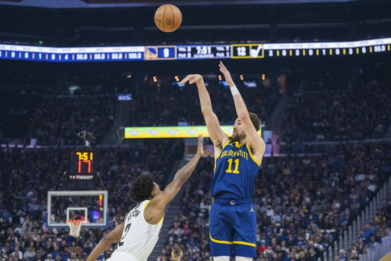 Klay Thompson (11), de los Warriors de Golden State, dispara un triple sobre Collin Sexton (2), del Jazz de Utah, durante la primera mitad del juego de baloncesto de la NBA, el domingo 7 de abril de 2024, en San Francisco. (AP Foto/Nic Coury)