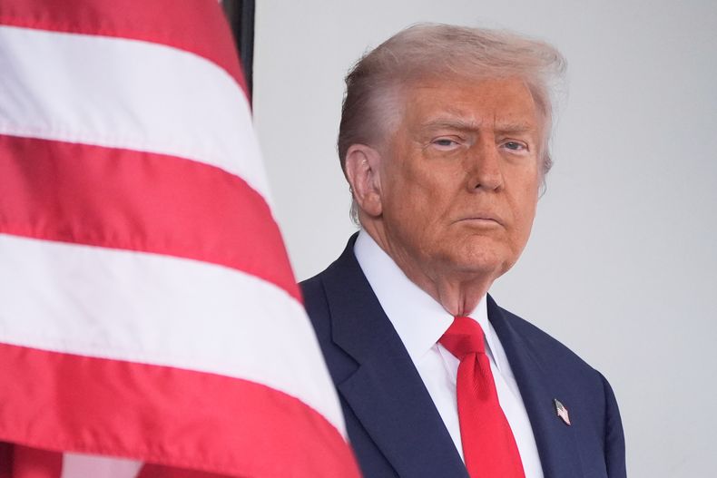 El presidente estadounidense Donald Trump espera para saludar al mandatario argentino Javier Milei a su llegada a la Casa Blanca, el martes 14 de octubre de 2025, en Washington. (AP Foto/Mark Schiefelbein)