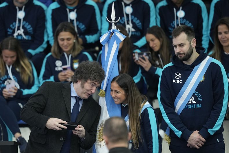 El presidente argentino Javier Mieli, a la izquierda, habla con la jugadora de hockey sobre césped Rocío Sánchez Moccia y el jugador de vóleibol Luciano De Cecco durante la ceremonia de despedida de los atletas argentinos que competirán en los Juegos Olímpicos de París, en Buenos Aires, Argentina, viernes 5 de julio, 2024. (AP Foto/Natacha Pisarenko)