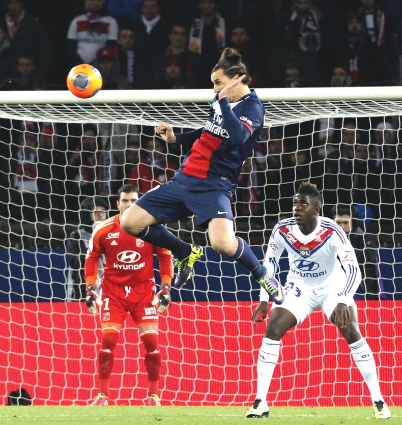 El sueco Zlatan Ibrahimovic, del Paris Saint Germain, se eleva para cabecear un bal&oacute;n ante el portero del Lyon Remy Vercoutre mientras Samuel Um Titti lo observa durante un partido de la liga francesa, el domingo 1 de diciembre de 2013, en el estad