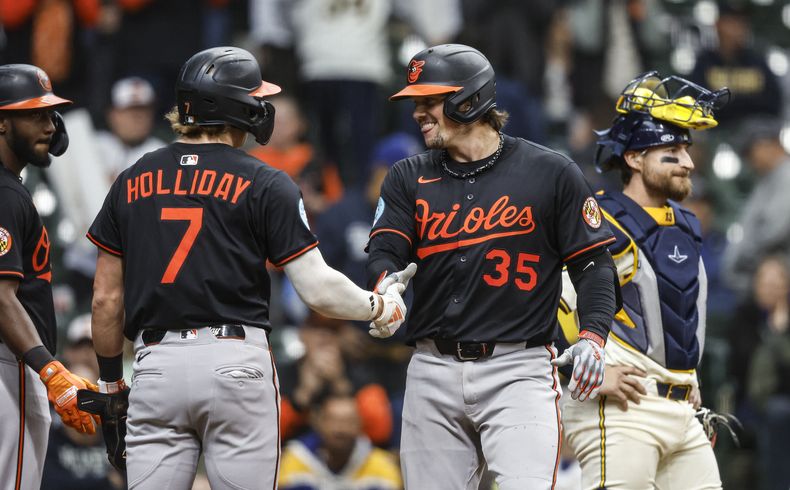 Adley Rutschman (35), de los Orioles de Baltimore, es felicitado por Jackson Holliday (7) después de batear un jonrón de tres carreras durante la 11ma entrada del juego de béisbol de Grandes Ligas frente a los Cerveceros de Milwaukee, el miércoles 21 de mayo de 2025, en Milwaukee. (AP Foto/Jeffrey Phelps)