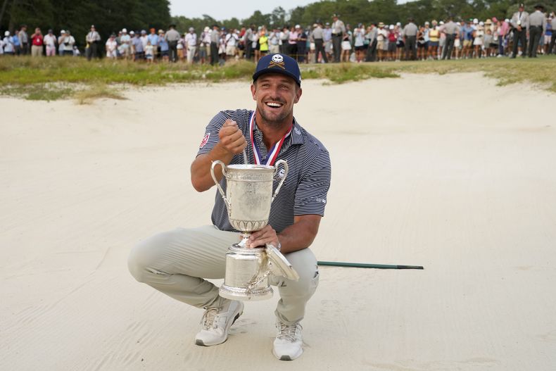 Bryson DeChambeau sostiene el trofeo dentro del bunker después de ganar el torneo de golf U.S. Open, el domingo 16 de junio de 2024, Pinehurst, Carolina del Norte. (AP Foto/Matt York)