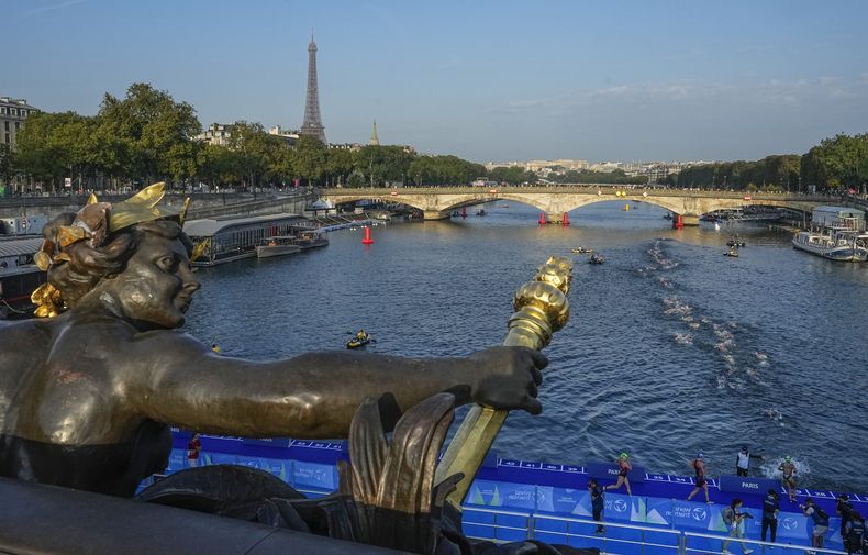Foto del jueves 17 de agosto del 2023, atletas saltan y nadan en el río Sena cerca del puente Alexander III en la primera etapa del evento de prueba del triatlón para los Juegos Olímpicos 2024. (AP Foto/Michel Euler)