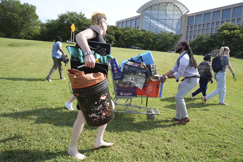 Voluntarios ayudan a personas sin hogar a retirar sus pertencencias de un campamento para indigentes, en Washington, el 14 de agosto de 2025. (AP Foto/Jacquelyn Martin)