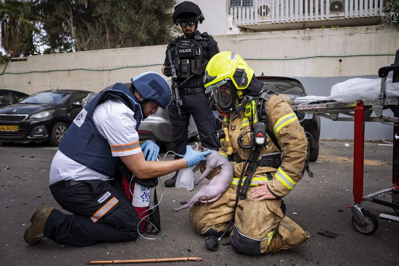 Un bombero y un paramédico administran oxígeno a un gato herido rescatado de un edificio alcanzado por un proyectil disparado desde Gaza, en Tel Aviv, Israel, el 27 de octubre de 2023. (AP Foto/Oded Balilty)