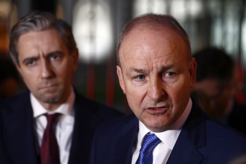 El líder del partido Fianna Fail, Micheal Martin, derecha, y Simon Harris, de Fine Gael, hablan con los medios fuera de la sede del gobierno en Dublín, el miércoles 22 de enero de 2025. (AP Foto/Peter Morrison)