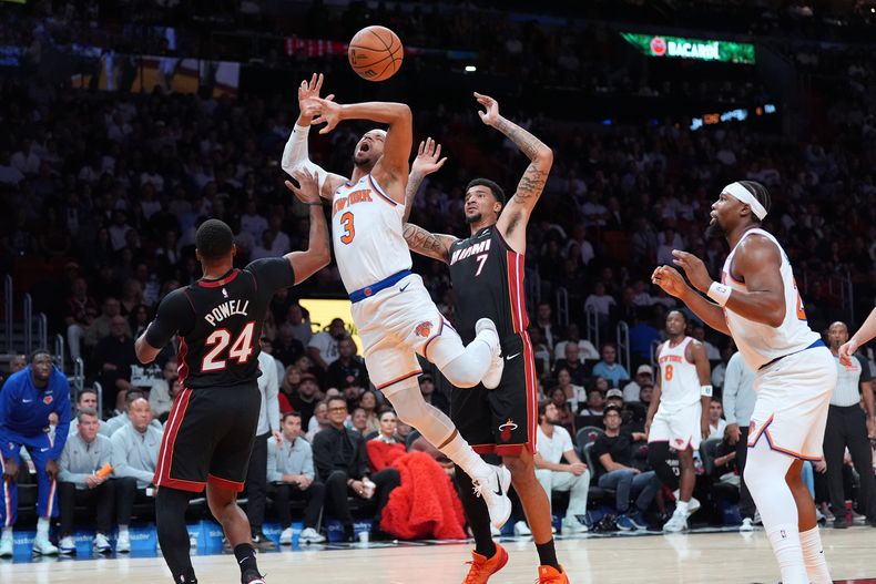 Josh Hart (3), guardia de los Knicks de Nueva York, recibe una falta de Norman Powell (24), guardia del Heat de Miami, mientras Kelel Ware (7), pívot del Heat de Miami, observa durante la primera mitad de un juego de baloncesto de la NBA, el domingo 26 de octubre de 2025, en Miami. (AP Photo/Rebecca Blackwell)