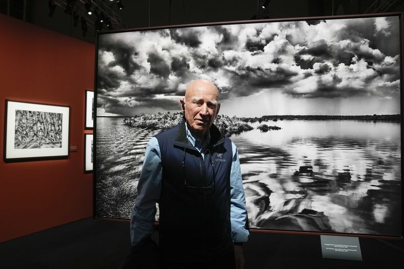 ARCHIVO – El fotógrafo brasileño Sebastiao Salgado posa frente a una de las fotografías de su muestra “Amazonía”, en la Fabbrica del Vapore, en Milán, Italia, el jueves 11 de mayo de 2023. (AP Foto/Luca Bruno, Archivo)