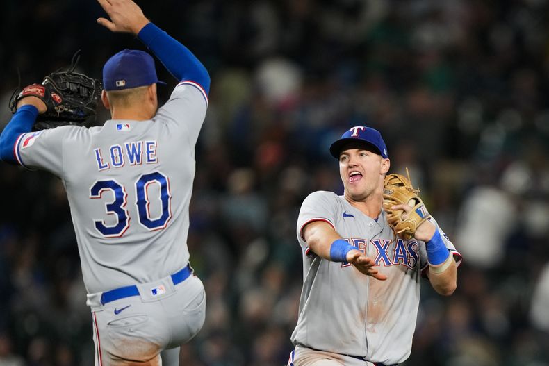 El primera base de los Rangers de Texas Nathaniel Lowe celebra con el tercera base después de que el equipo confirmó su lugar en la postemporada con la victoria ante los Marineros de Seattle el sábado 30 de septiembre del 2023. (AP Foto/Lindsey Wasson)
