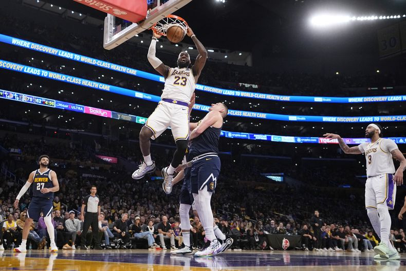 El alero de los Lakers de Los Ángeles LeBron James clava el balón frente al pívot de los Nuggets de Denver Nikola Jokic en el juego 4 de la serie de primera ronda el sábado 27 de abril del 2024. (AP Foto/Mark J. Terrill)