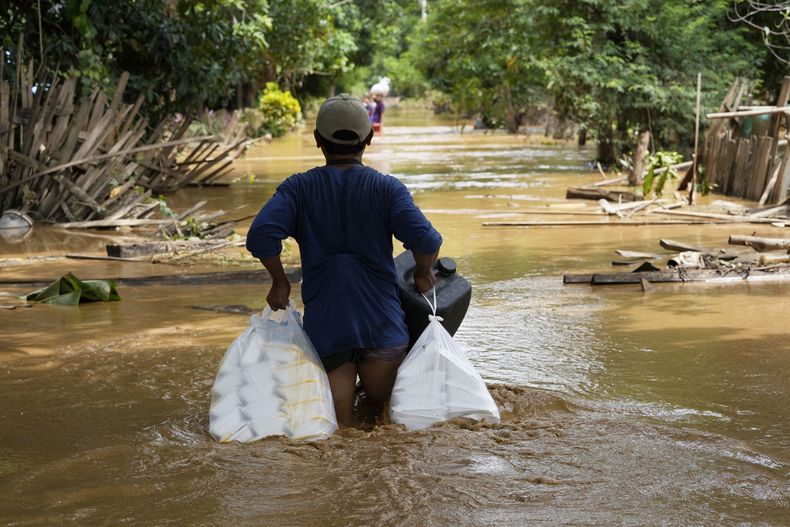 ARCHIVO - Residentes locales cargados de alimentos vadean una carretera inundada en Naypyitaw, Myanmar, el sábado 14 de septiembre de 2024. (AP foto/Aung Shine Oo, archivo)