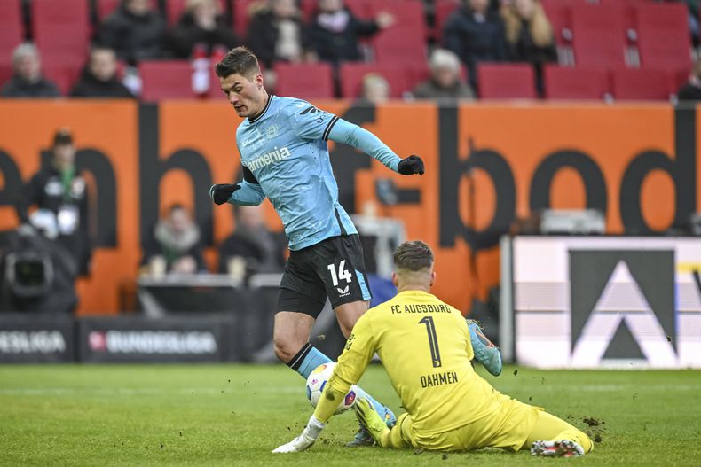 El portero del Augsburg Finn Dahmen intenta desviar el balón mientras Patrik Schick del Bayern Leverkusen gambetea en el encuentro de la Bundesliga el sábado 13 de enero del 2024. (Harry Langer/dpa via AP)