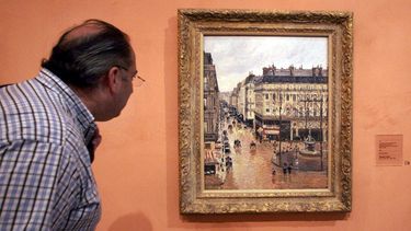 ARCHIVO - Un visitante observa el cuadro impresionista titulado Rue St.-Honore, Apres-Midi, Effet de Pluie (Calle Saint-Honoré por la tarde, efecto de lluvia) pintado en 1897 por Camille Pissarro, expuesto en el Museo Thyssen-Bornemisza el 12 de mayo de 2005, en Madrid. (AP Photo/Mariana Eliano, File)