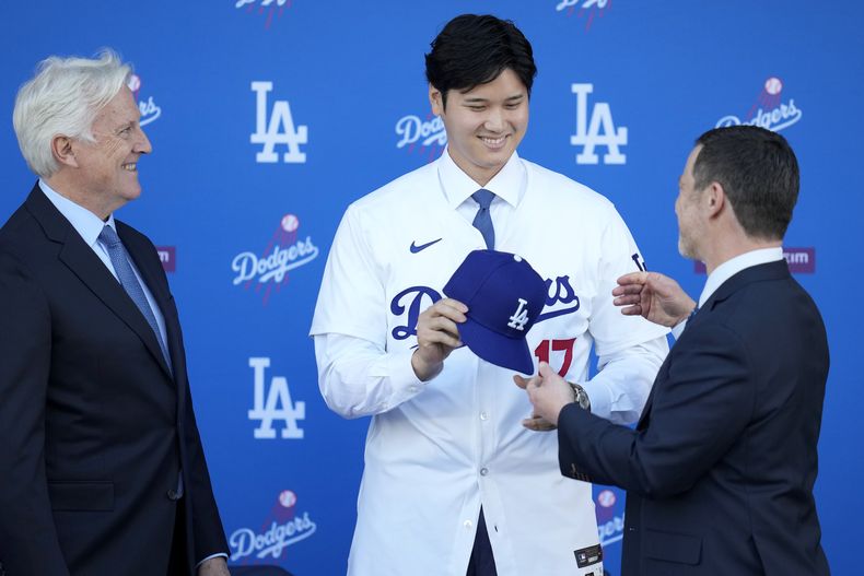 Shohei Ohtani recibe una gorra de manos de Andrew Friedman, presidente de operaciones deportivas de los Dodgers de Los Ángeles, el jueves 14 de diciembre de 2023 (AP Foto/Ashley Landis)
