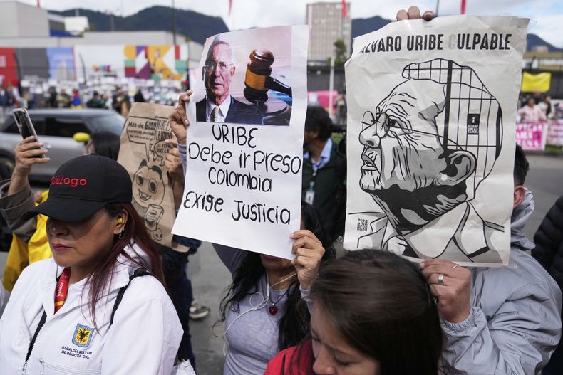 Opositores al expresidente Álvaro Uribe se reúnen afuera del tribunal el día en que fue sentenciado a 12 años de arresto domiciliario por manipulación de testigos y soborno en Bogotá, Colombia, el viernes 1 de agosto de 2025. (AP Foto/Fernando Vergara)