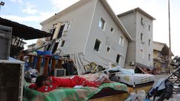 Un niño duerme en la calle ante casas dañadas por los sismos en Catia La Mar, Venezuela, el domingo 28 de junio de 2026. (AP Foto/Pedro Mattey)