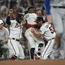 Ozzie Albies (centro) es felicitado por sus compañeros tras empujar la carrera del triunfo sobre los Dodgers de Los Ángeles, el miércoles 24 de mayo de 2023 (AP Foto/John Bazemore)