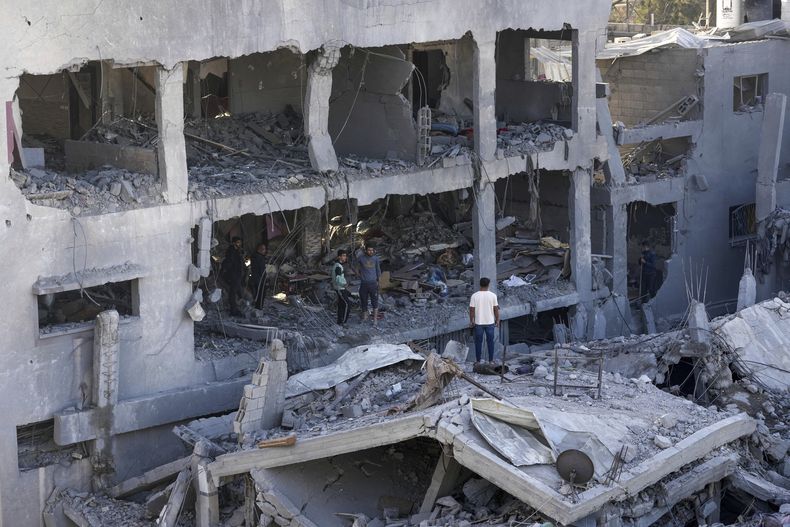 Palestinos buscan entre los escombros de un edificio destruido en el que murió la familia Muharib durante un bombardeo israelí, el jueves 23 de noviembre de 2023, en el campamento de refugiados Nusseirat, en la Franja de Gaza. (AP Foto/Adel Hana)