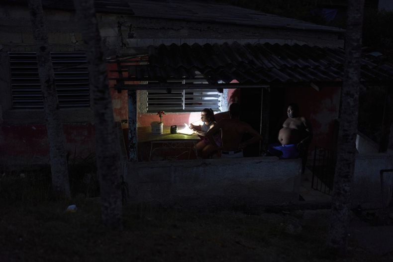 Una persona usa una linterna para iluminarse en su porche durante un apagón en La Gallega, La Habana, Cuba, el domingo 1 de junio de 2025. (AP Foto/Ramón Espinosa)