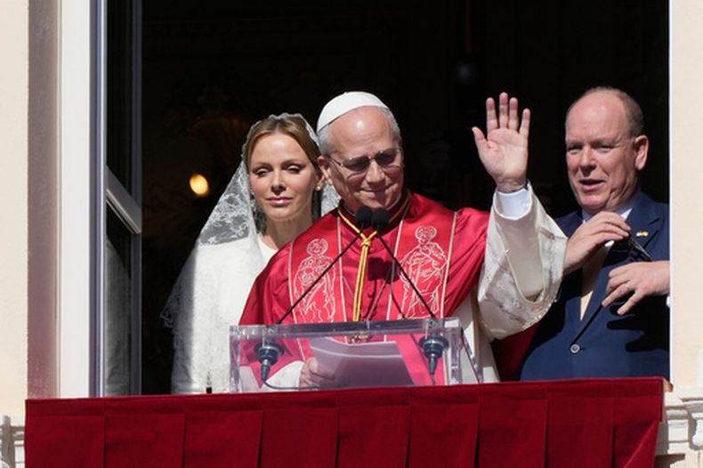 El papa León XIV y los príncipes Charlene y Alberto II de Mónaco, saludan desde el balcón de la Galería de Hércules, en el palacio de los monarcas en Monaco-Ville, Mónaco, el 28 de marzo de 2026. (AP Foto/Gregorio Borgia)