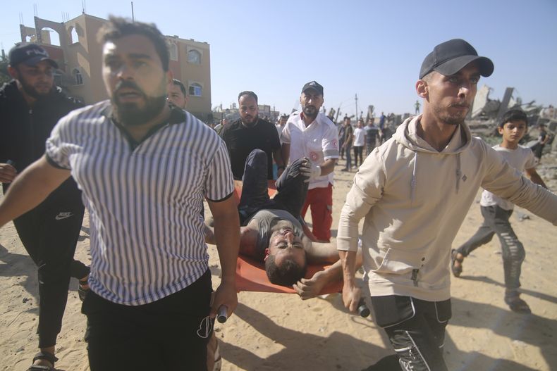 Palestinos llevan a un hombre herido de entre los escombros de un edificio derruido tras un ataque aéreo en Rafah, en la Franja de Gaza, el viernes 13 de octubre de 2023. (AP Foto/Hatem Ali)