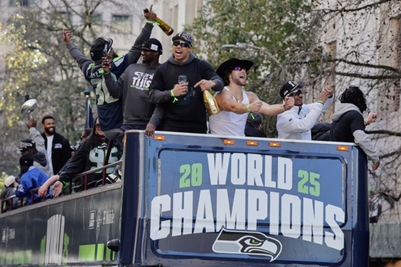 Jugadores de los Seahawks de Seattle festejan en la parte alta de un autobús durante el desfile para celebrar el título del Super Bowl en Seattle el miércoles 11 de febrero del 2026. (AP Foto/John Froschauer)