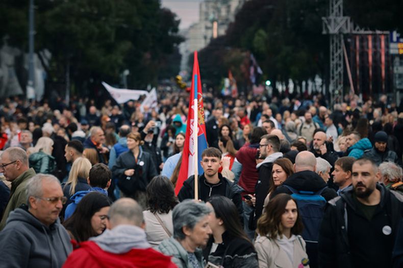 Un joven sostiene una bandera serbia mientras la gente se reúne para la marcha Lista estudiantil - Los estudiantes ganan antes de las elecciones parlamentarias, en Belgrado, Serbia, el jueves 22 de octubre de 2026. (AP Foto/Marko Drobnjakovic)
