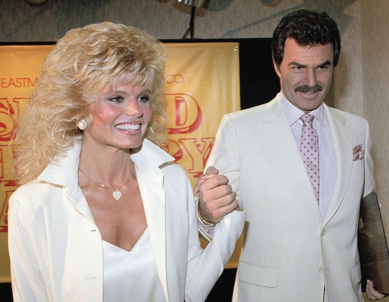 ARCHIVO - Burt Reynolds, derecha, sostiene la mano de Loni Anderson en un almuerzo, el 27 de marzo de 1987, en Los Ángeles. (AP Foto/Bob Galbraith, archivo)