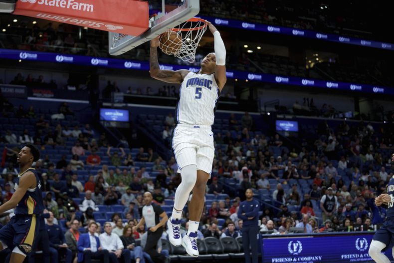 El alero del Magic de Orlando Paolo Banchero (5) se libera para una volcada contra el escolta de los Pelicans de Nueva Orleans, Trey Murphy III (25), durante la segunda mitad de un partido de baloncesto de la NBA en Nueva Orleans, el jueves 13 de marzo de 2025. (AP Foto/Matthew Hinton)