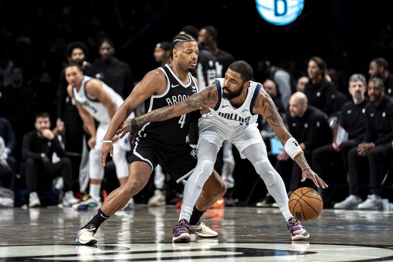 El armador de los Mavericks de Dallas Kyrie Irving (derecha) es marcado por el base de los Nets de Brooklyn Dennis Smith Jr. (4) durante la segunda mitad del juego de baloncesto de la NBA, en Nueva York, el martes 6 de febrero de 2024. (AP Foto/Peter K. Afriyie)