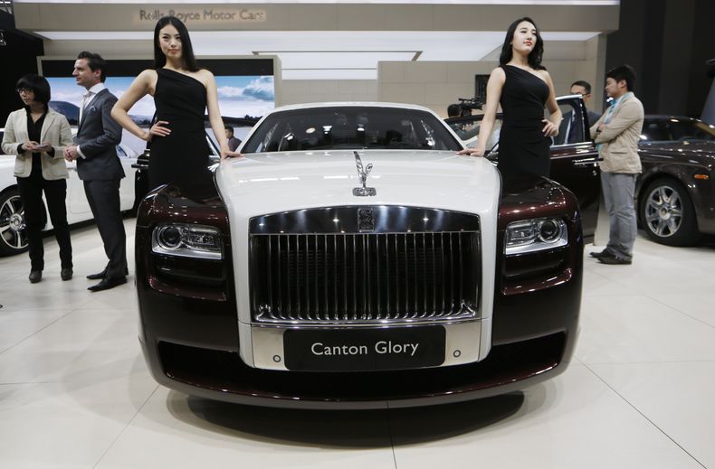 ARCHIVO - En esta foto de archivo del 21 de noviembre de 2013, modelos posan junto al Rolls-Royce Canton Glory en la muestra de autos de Guangzhou, China. Rolls-Royce dijo el martes 8 de julio de 2014 que sus ventas globales en el primer semestre aumentar