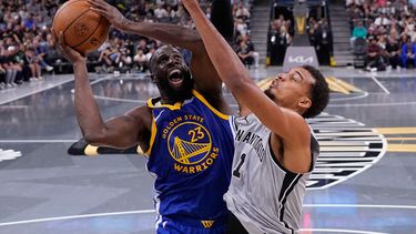 Draymond Green (23), alero de los Warriors de Golden State, conduce al aro contra Victor Wembanyama (1), alero de los Spurs de San Antonio, durante la segunda mitad de un juego de baloncesto de la Copa NBA en San Antonio, el viernes 14 de noviembre de 2025. (AP Photo/Eric Gay)