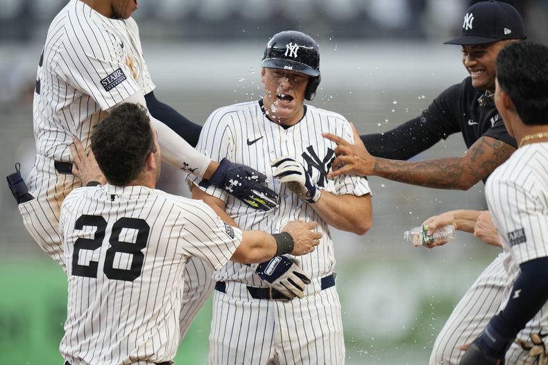 DJ LeMahieu, centro, de los Yankees de Nueva York, celebra con sus compañeros de equipo después de batear un sencillo productor para dejar tendidos a los Azulejos de Toronto en la 10ma entrada del juego de béisbol del domingo 4 de agosto de 2024, en Nueva York. (AP Foto/Seth Wenig)